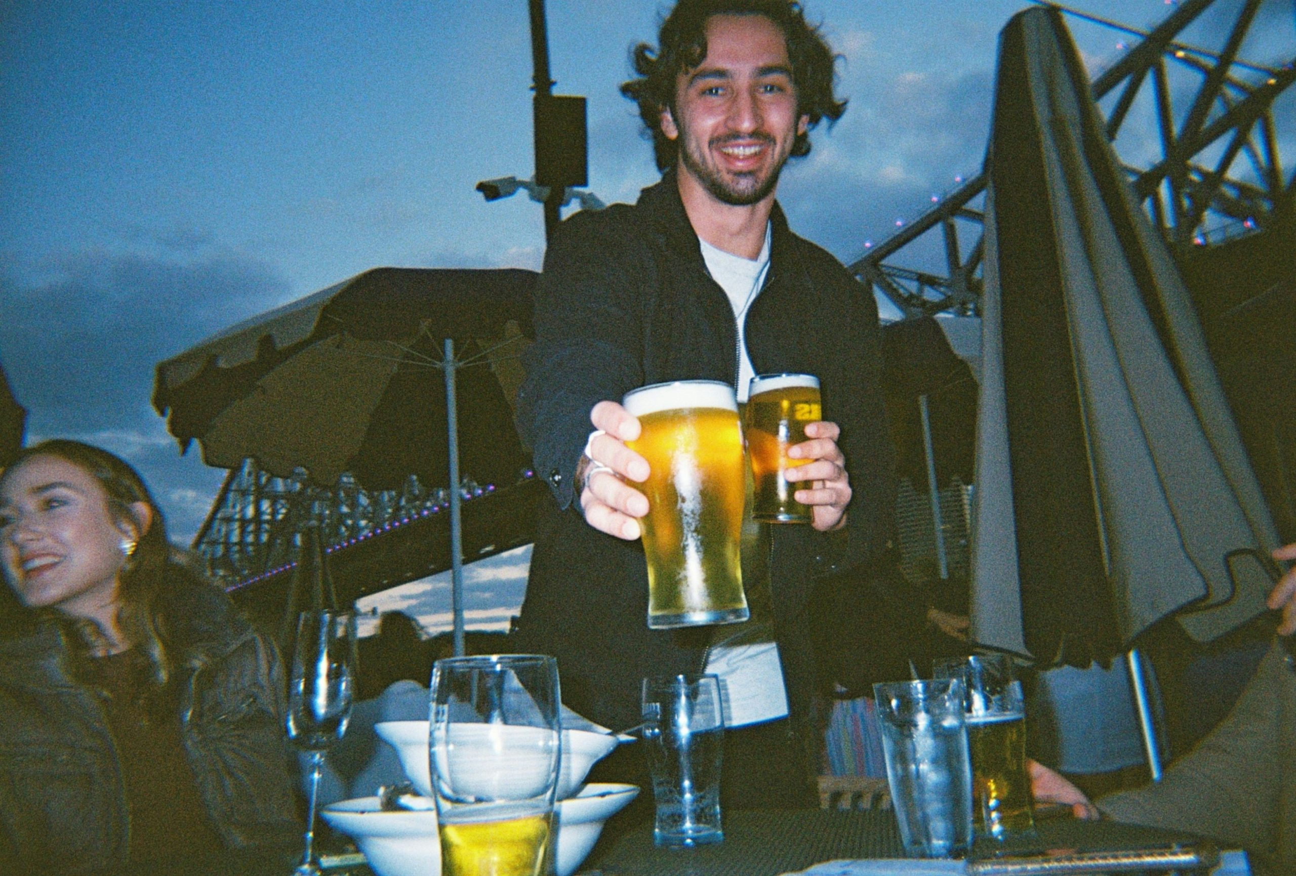 Image of person offering a beer and raising the question what is drink driving?
