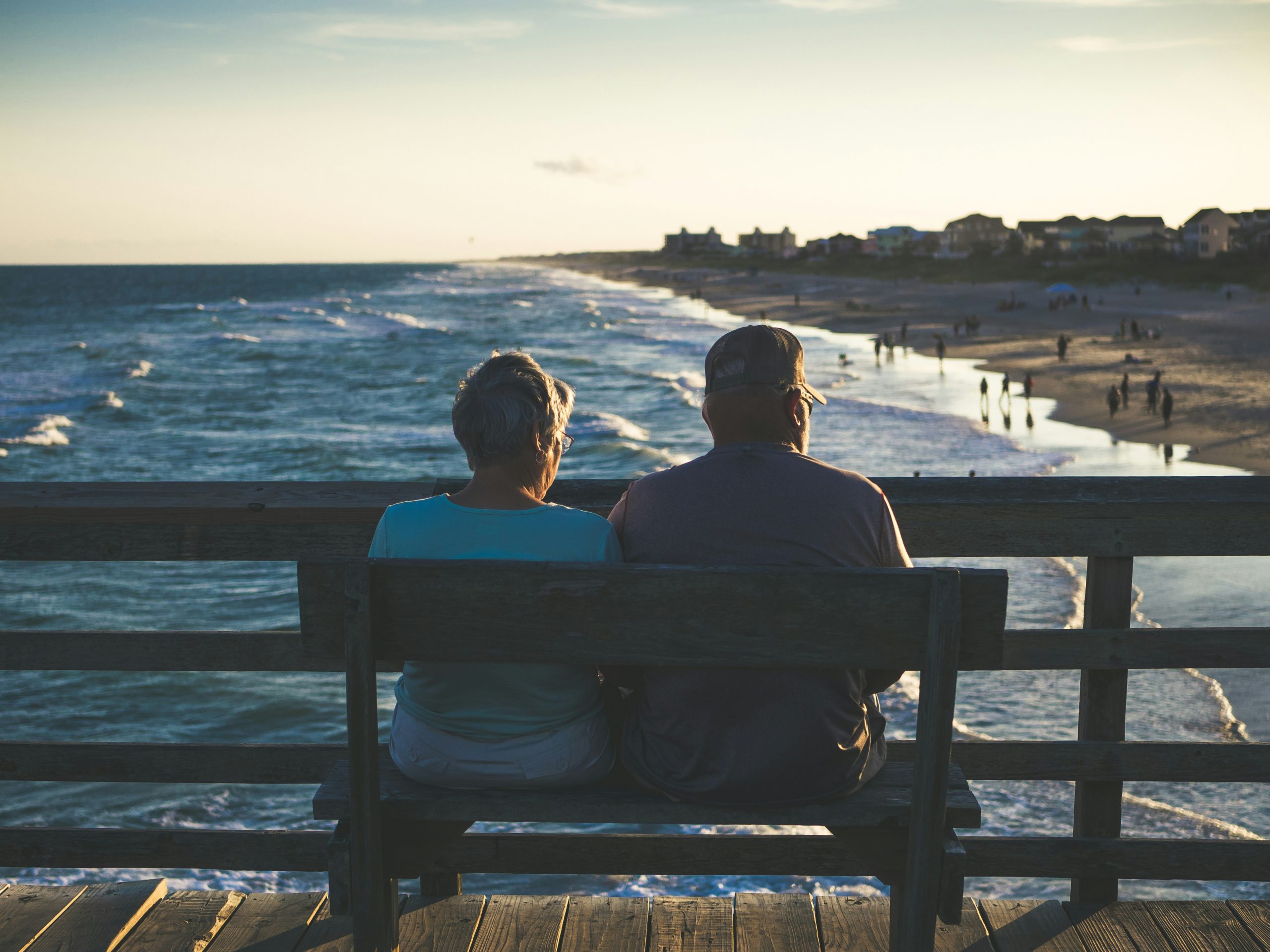 elderly couple sitting on seat overlooking the beach contemplating the prevalence of elder abuse